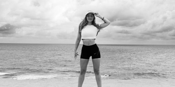 Black and white photo of a woman standing at the beach in Natal, Brazil, enjoying the ocean view.