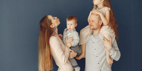 Portrait of a joyful family with parents and kids showing love and affection against a blue background.